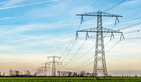 Hoogspanningsmasten in een open landschap bij zonsondergang
